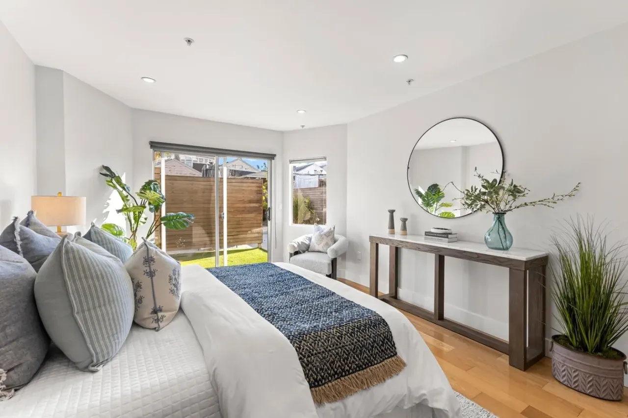 Staged bedroom with a navy throw, a wood console with a round mirror and sliding doors to the yard