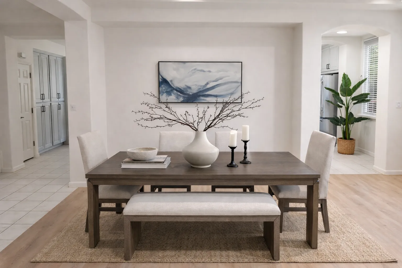 Staged dining room with a dark wood table, upholstered bench and blue abstract art