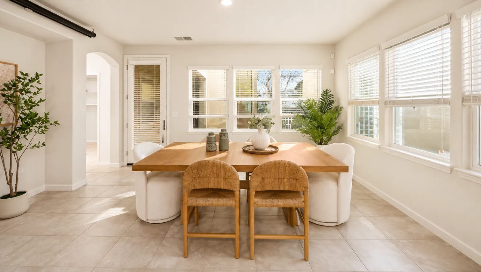 Staged breakfast nook with a light wood table and woven chairs on a tile floor