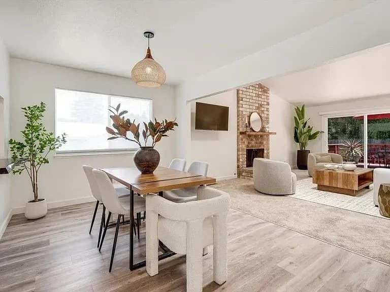 Staged open-plan dining and living area with a brick fireplace
