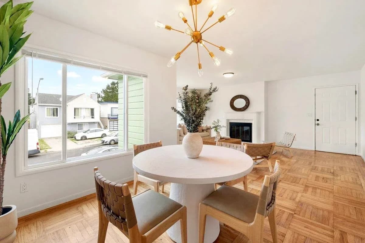 Staged dining room with a round white table and a brass sputnik chandelier