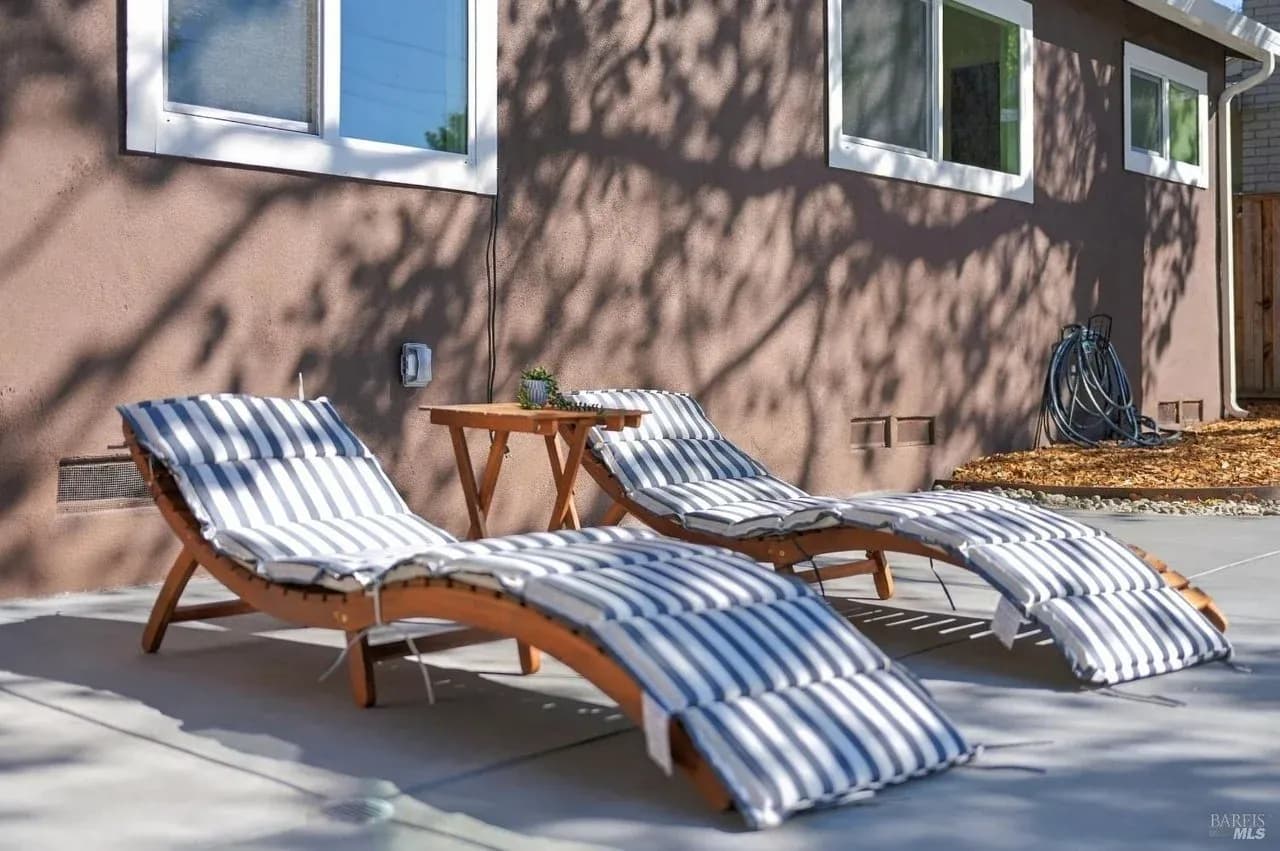 Staged patio with two striped lounge chairs in dappled sunlight