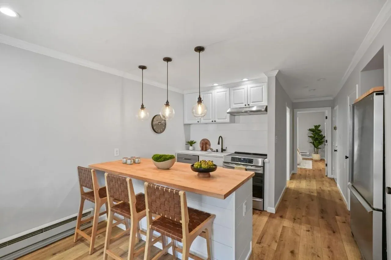Staged kitchen with a butcher block island and woven leather barstools