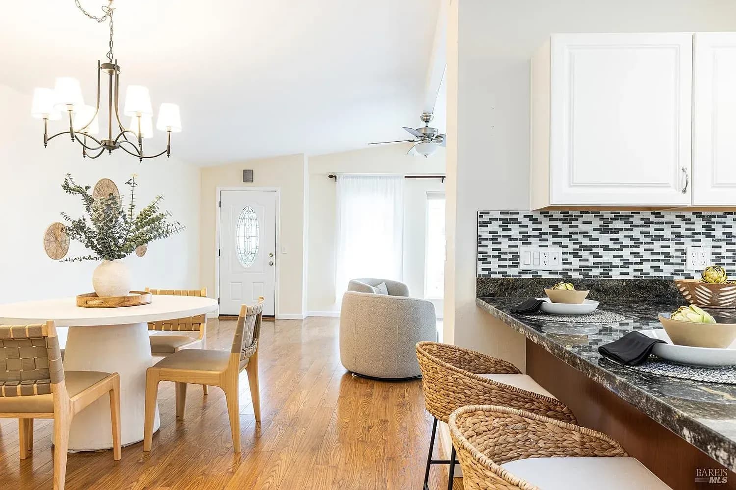 Staged open-plan kitchen and dining room with rattan barstools and a round white table