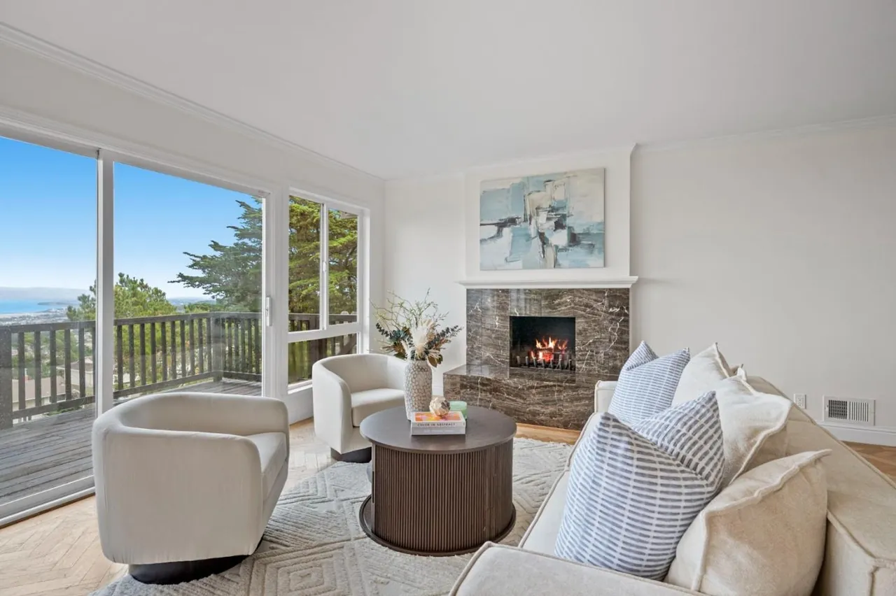 Staged San Bruno living room with a bay view, swivel chairs, a round coffee table and a stone fireplace