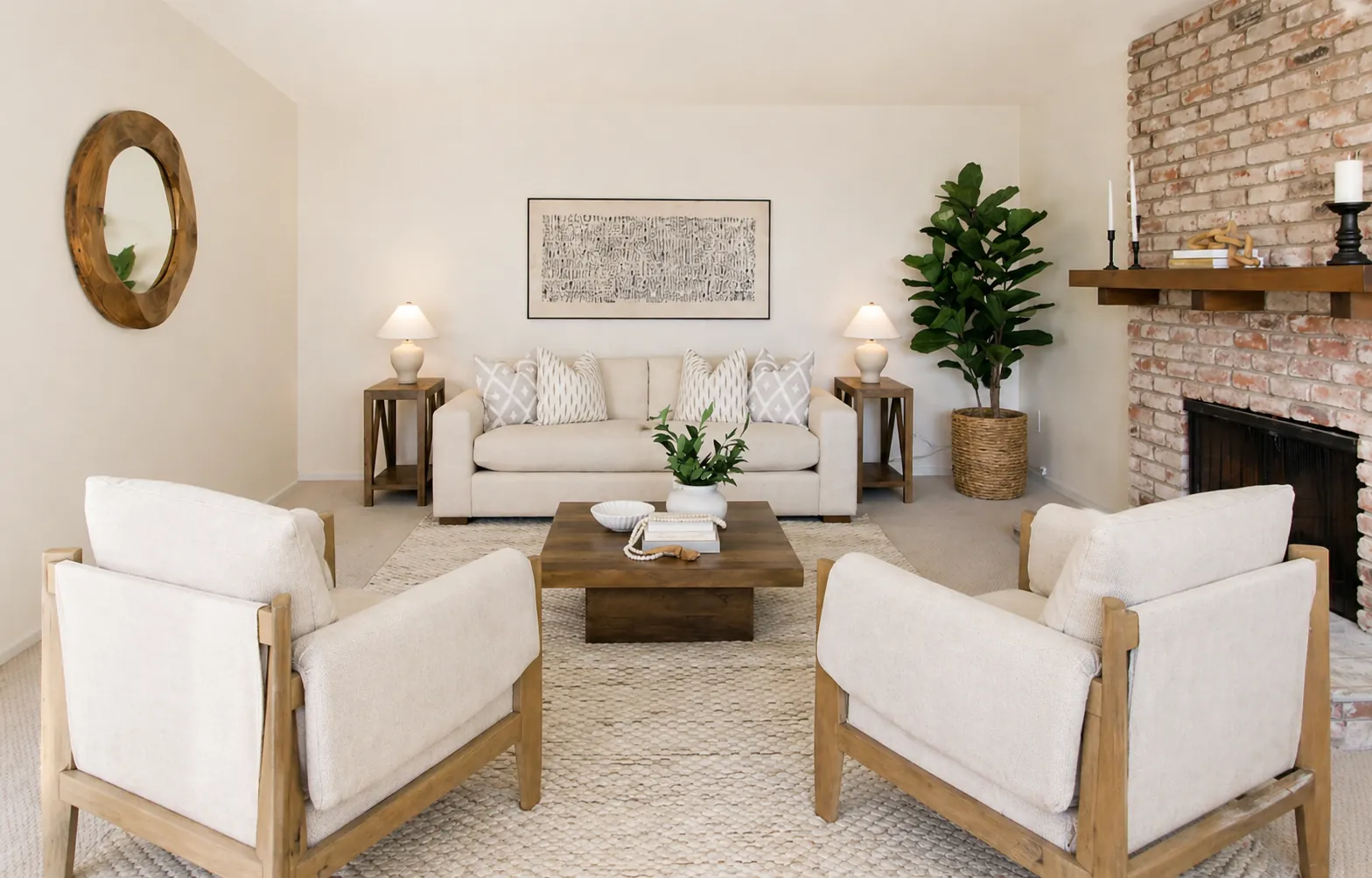 Staged living room with a cream sofa, wood-framed armchairs and a brick fireplace