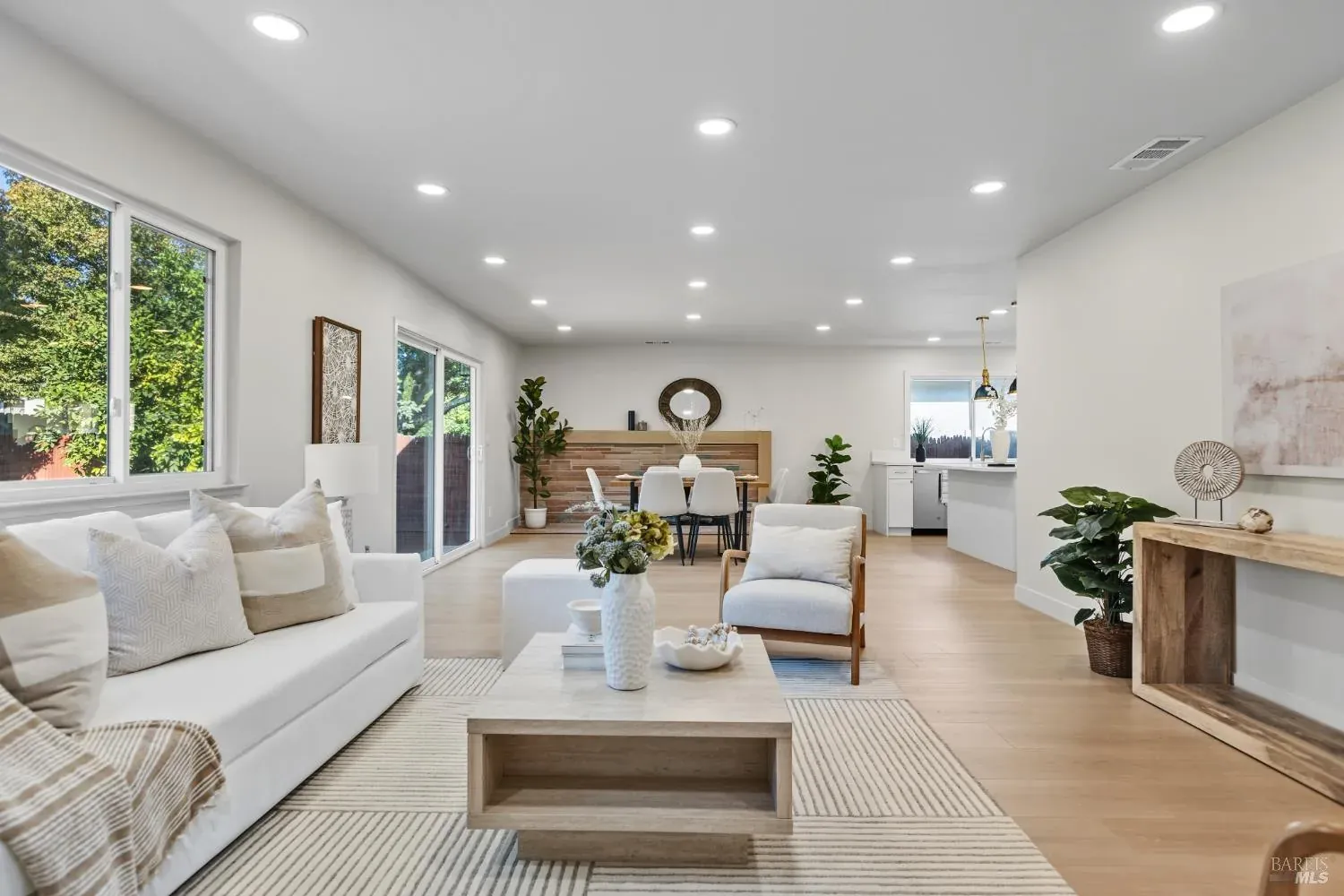 Staged open-plan living room with a cream sofa, wood coffee table and a console table