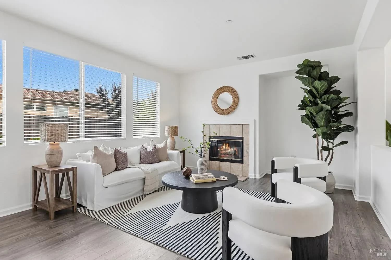Staged living room with a white slipcovered sofa, striped rug and fireplace
