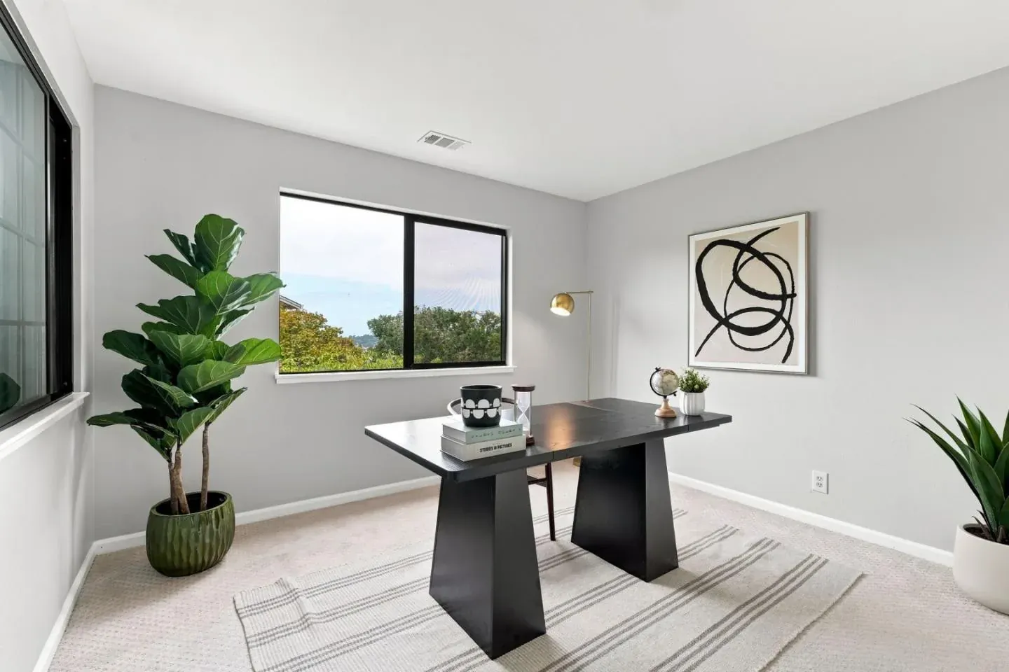 Staged home office with a black pedestal desk, a fiddle-leaf fig and abstract art