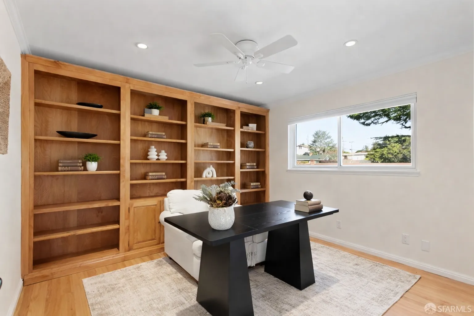 Staged home office with wood built-in shelving and a black pedestal desk