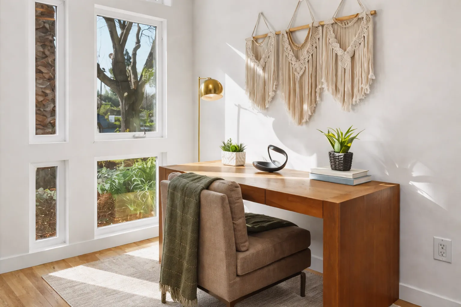 Staged home office with a wood desk, leather chair and macramé wall hanging