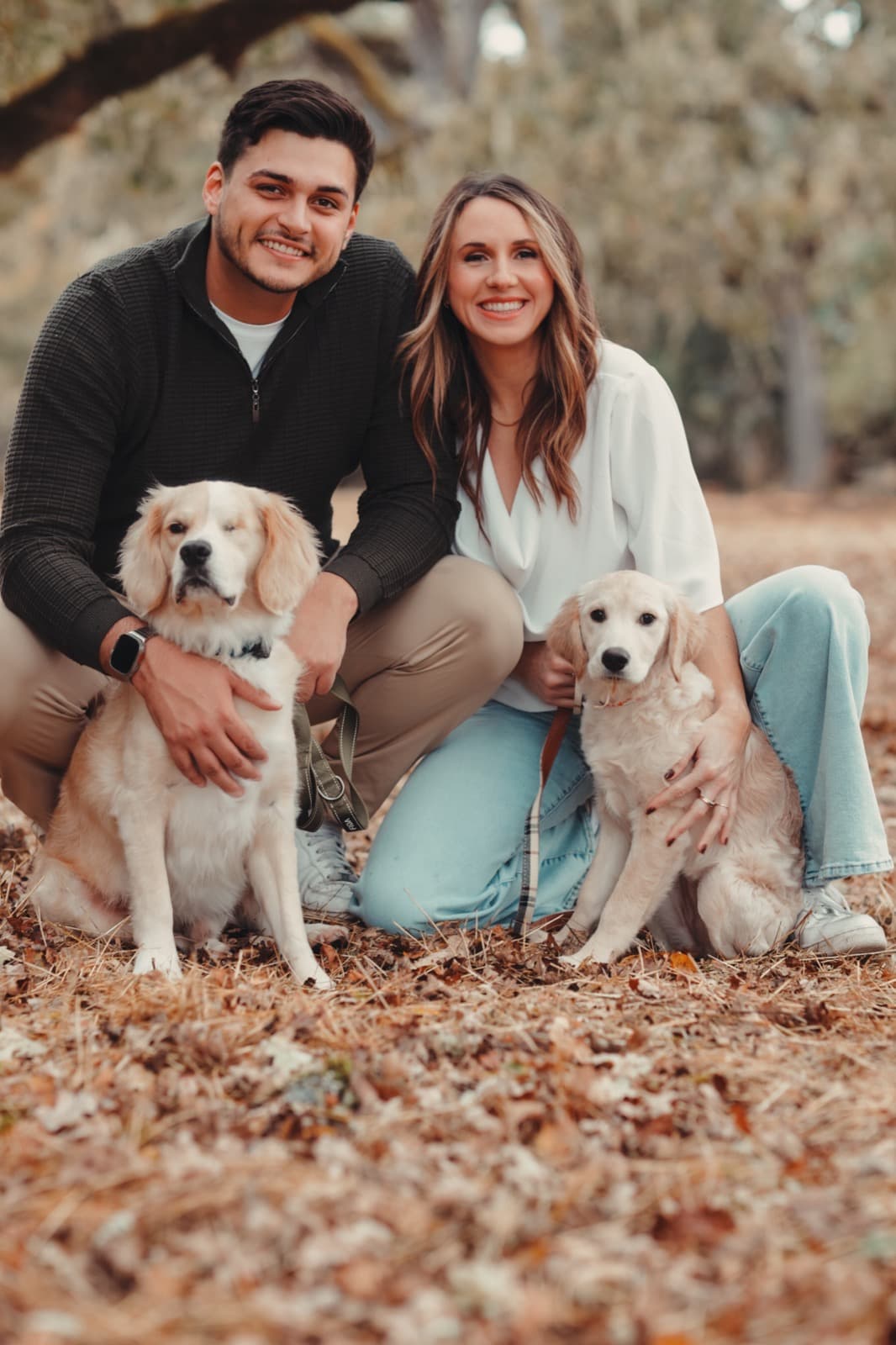 Gabriel Skoog and Georgia Mowry of Easy Stage, crouching in autumn leaves with their two golden retrievers